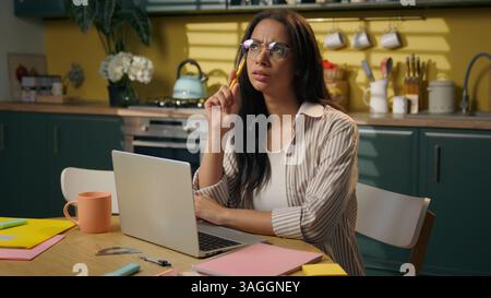 Denken Arabische indische Latina ethnische nachdenkliche Geschäftsfrau weibliches Mädchen Geschäftsfrau Freelancer denken nachdenkliche Studie Laptop zu Hause Küche kommen Stockfoto