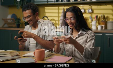 Multiethnische Teenager Studenten Mädchen Guy Afroamerikaner Mann Arabische Frau studieren zu Hause Küche Smartphone süchtig Freunde Paar Spieler spielen Stockfoto