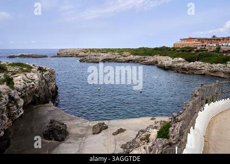 Eine malerische Aussicht auf Binibeca, Menorca, mit Blick auf die felsige Küste und das ruhige Meer unter klarem Himmel. Das Foto zeigt eine ruhige und malerische Küste Stockfoto