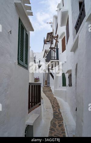 Ein malerischer Blick auf eine enge Straße in Binibeca, Menorca, mit weißen Gebäuden und einem Steinweg. Stockfoto