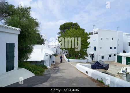Eine ruhige Straßenszene in Binibeca, Menorca, mit den berühmten weiß getünchten Gebäuden und der charmanten Architektur der Gegend. Stockfoto