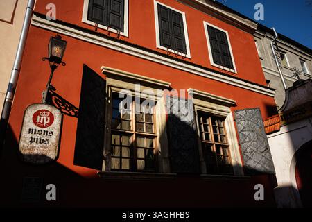Lemberg, Ukraine - 07. April 2025: Schöne Mons Pius-Architektur mit roter Fassade, sonnigen Fenstern und kunstvollen schwarzen Fensterläden. Stockfoto