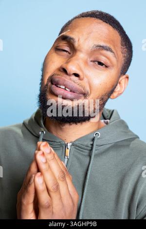 Ein hoffnungsvoller afroamerikaner bettelt und bittet um etwas, bittet um Vergebung oder Barmherzigkeit und ist traurig. Armer Bettler bittet um Hilfe, fleht und ist verzweifelt. Stockfoto