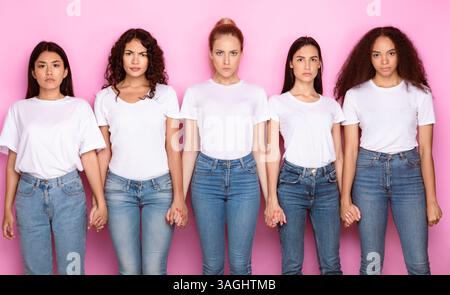 Unzufrieden Multiethnische Frauen Halten Hände Stehen Über Rosa Hintergrund Stockfoto