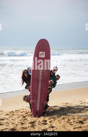 Lancau, Frankreich 04.09.2025 Gruppe mit rotem Surfbrett, die Spaß am sonnigen Tag am Strand hat Stockfoto