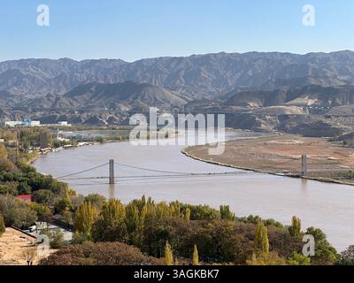 Eine atemberaubende Landschaft mit einer Brücke über einen breiten Fluss mit Bergen in der Ferne. Stockfoto