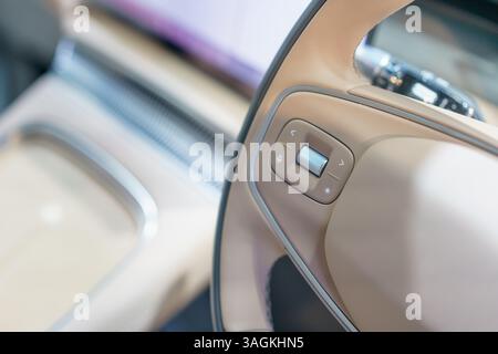 Nahaufnahme der fortschrittlichen Lenkradbedienelemente in einem eleganten Innenraum eines Elektroautos mit Schwerpunkt auf modernem Design und benutzerfreundlicher Technologie Stockfoto