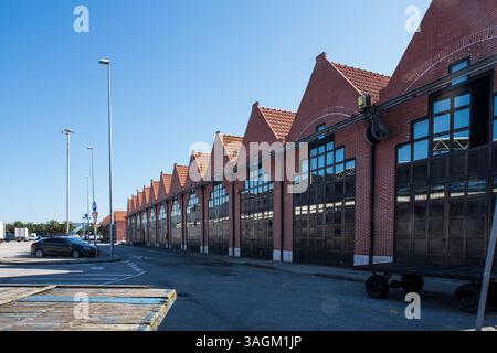 Alte Architektur in roten Ziegelsteinen und schwarzen Metalltüren von Fischerhallen am Hafen von Santona in Kantabrien in Spanien am Meer Stockfoto