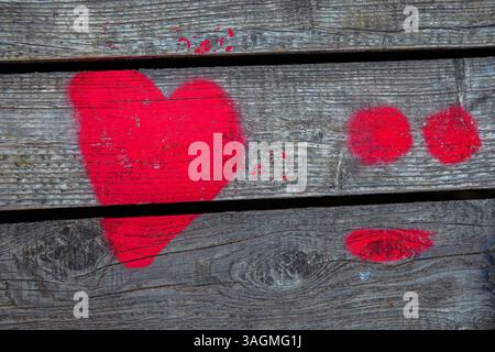 Love Heart Spray gemalt auf hölzernem Wandhintergrund. Ein rotes Herz auf Holzbrettern, Zaun Hintergrund. Alles Gute zum Valentinstag. 14. Februar Hintergrundbild, Design Stockfoto