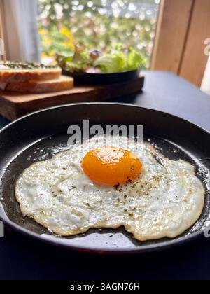 Ein einzelnes Spiegelei in einer Pfanne, serviert mit Gemüse und Brot auf dem Tisch. Gesundes Lebensmittelkonzept. Nahaufnahme. Stockfoto