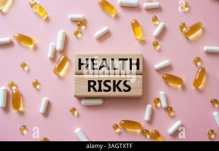 Symbol für Gesundheitsrisiken. Konzeptwort Gesundheitsrisiken auf Holzklötzen. Schöner rosafarbener Hintergrund mit Pillen. Medizin und Gesundheitsrisiko-Konzept. Kopierbereich Stockfoto