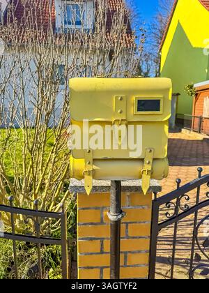 Gelbes Postfach auf Brick Post, Vorstadtszene, Sonnentag, Wohngebiet. Hochwertige Fotos Stockfoto