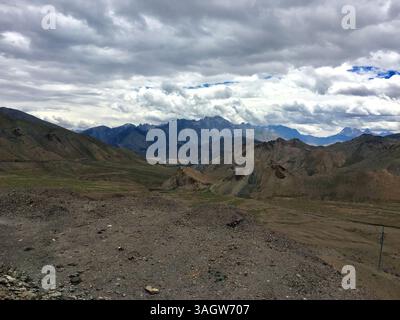 Ein atemberaubender Blick auf Leh Ladakh offenbart weitläufige Hügel und dramatische Bergketten, alles unter einem dynamischen wolkengefüllten Himmel. Stockfoto