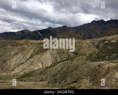 Ein atemberaubender Blick auf Leh Ladakh offenbart weitläufige Hügel und dramatische Bergketten, alles unter einem dynamischen wolkengefüllten Himmel. Stockfoto