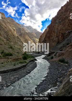 Der sich windende Fluss fließt durch zerklüftete Berge in Leh Ladakh, umgeben von felsigem Gelände und dramatischen Wolkenformationen darüber. Stockfoto