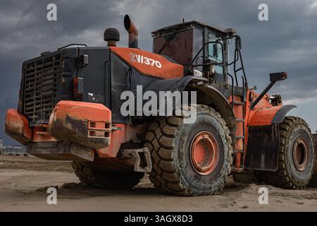 Schwere Maschinen Hitachi Zw Radlader in Aktion, die Sand aufnehmen. Ansicht eines orangefarbenen Radladers Hitachi ZW370 für Erdarbeiten auf der Baustelle. Stockfoto