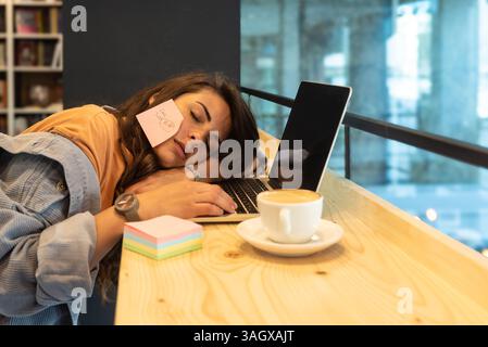 Junge freischaffende Geschäftsfrau, müde und müde von der Arbeit, die faul in der Bibliothek auf Laptop-Computer arbeitet. Gestresste und ängstliche weibliche Überlastung des Gehirns Stockfoto
