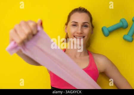 Widerstandsbandübungen. Die Frau legt sich auf eine gelbe Fitnessmatte und macht Workout. Draufsicht Stockfoto