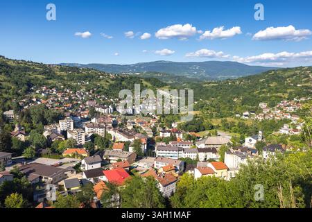 Jajce Stadt in Bosnien und Herzegowina, Europa. Malerischer Blick auf Häuser und Gebäude, eingebettet in sanfte Hügel und Berge, vor einem leuchtend blauen Himmel wi Stockfoto