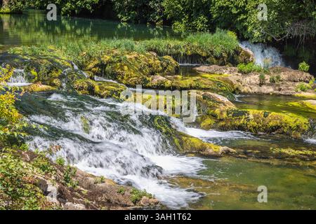 Kocusa Wasserfall im Dorf Veljaci, Bosnien und Herzegowina, Europa. Malerischer Wasserfall über moosige Felsen, umgeben von üppigem Grün in der Sonne Stockfoto