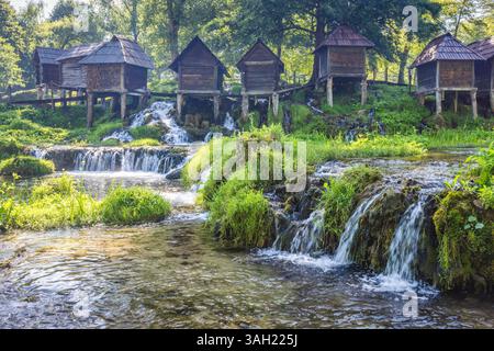 Die Holzwassermühlen Mlincici am Fluss Pliva in der Nähe der Stadt Jajce in Bosnien und Herzegowina, Europa. Rustikale Wassermühlen, die über Wasserfällen thronen, schaffen Stockfoto