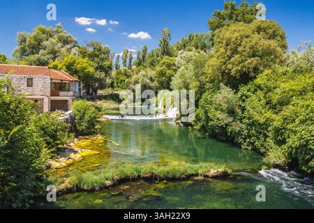 Kocusa Wasserfall im Dorf Veljaci, Bosnien und Herzegowina, Europa. Riverside Haus eingebettet zwischen üppigem Grün, mit klarem türkisfarbenem Wasser und einem sma Stockfoto