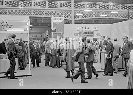 Besucher einer Fachmesse für Film- und Fotohersteller und Zulieferer in Olympia, West Kensington, Hammersmith, London, England, UK in c.1960. Am Specto Stand waren 8-mm-Cine-Kameras zu sehen. Specto aus Windsor, Berkshire, hat sich auf Heimkameras und Projektoren sowie Kassettenrekorder spezialisiert. Dahinter befindet sich ein Stand von View-Master, einem Unternehmen, das sich auf stereoskopische Betrachter für kleine Farbfotos (auf Plattenrollen aus Karton) spezialisiert hat und heute noch beliebt ist (jetzt von Mattel hergestellt). Das ist von einem alten Schwarzweiß-negativ eines Amateurfotografen – ein Vintage-Foto aus den 1950er/60er Jahren. Stockfoto