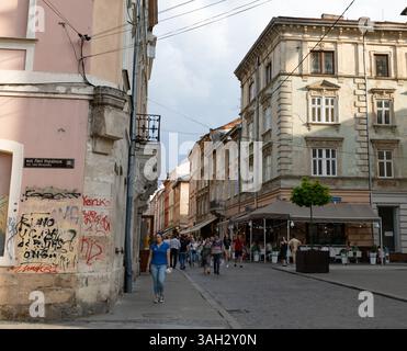LEMBERG, UKRAINE - 20. Juni 2021: Die Menschen schlendern durch die kopfsteingepflasterten Straßen des historischen Viertels, bewundern klassische Architektur und genießen die Cafés im Freien in der lebhaften Atmosphäre. Stockfoto