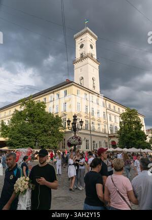 LEMBERG, UKRAINE - 20. Juni 2021: Bürger und Touristen schlendern durch die lebhaften Straßen, unterhalten sich und bewundern die Architektur unter den sich abzeichnenden grauen Wolken. Stockfoto