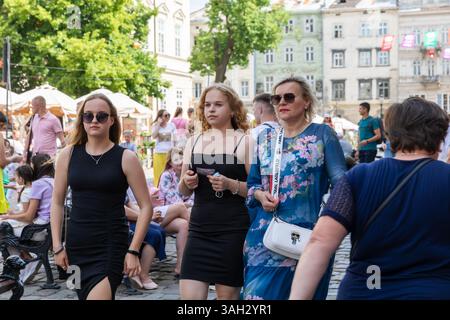LEMBERG, UKRAINE - 20. Juni 2021: Die Menschen durchqueren die Straßen der Altstadt von Lemberg, tauchen in die lebhafte Atmosphäre ein und genießen das warme Wetter in Cafés und Geschäften, während sie sich mit anderen unterhalten. Stockfoto