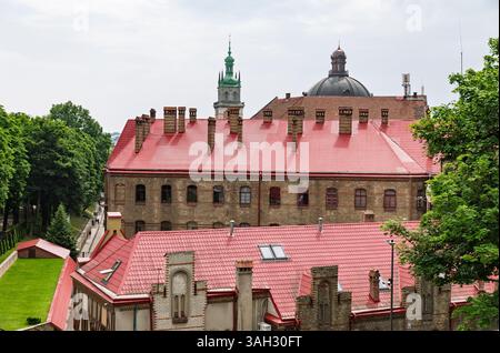 LEMBERG, UKRAINE - 20. Juni 2021: Historische Gebäude mit roten Dächern sind zwischen üppigem Grün sichtbar und zeigen die architektonische Schönheit der Stadt. Die Skyline ist durch Türme und Kuppeln gekennzeichnet. Stockfoto