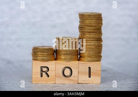 Return on Investment text on wooden cubes with stacking golden coins. ROI and investment concept. Stockfoto