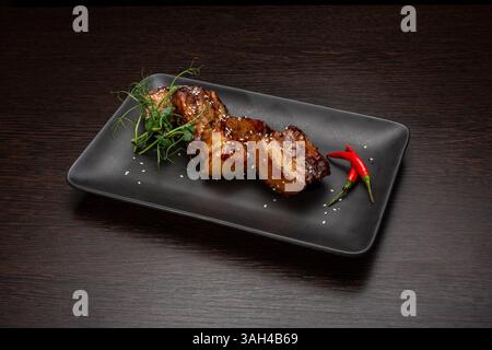 Gedünstetes Fleisch mit Sesam auf einem schwarzen Teller, japanische Küche Stockfoto