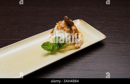 Dessert mit Blätterteig und Eis mit Karamell auf einem Teller Stockfoto