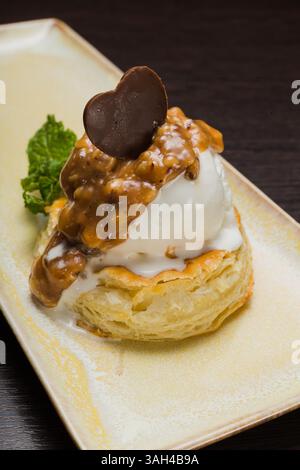Dessert mit Blätterteig und Eis mit Karamell auf einem Teller Stockfoto