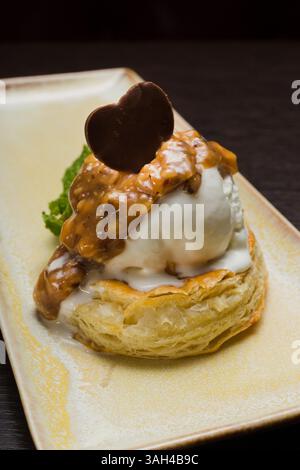 Dessert mit Blätterteig und Eis mit Karamell auf einem Teller Stockfoto