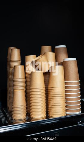 Stapel von Einweg-Kaffeetassen aus Papier liegen ordentlich auf einer Aufwärmschale und sind betriebsbereit. Stockfoto