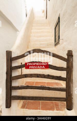 Ein Schild mit dem Text in spanischer Sprache, Privatbesitz, an einem stilvollen Holztor eines der Häuser in Binibeca, Menorca, Spanien Stockfoto