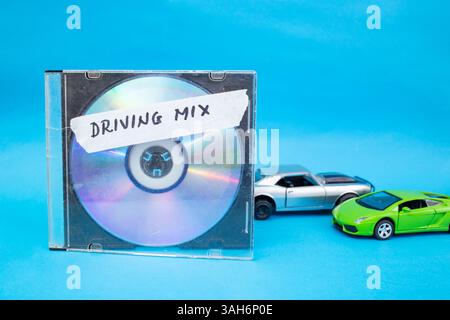 CD neben Spielzeugautos auf blauem Hintergrund und Fahrgemisch-Wörter, die auf Band geschrieben sind Stockfoto