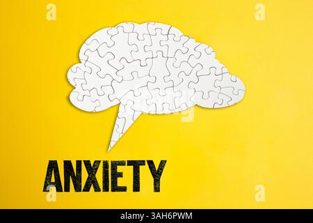 Puzzle Gehirnform Sprechblase auf gelbem Papphintergrund mit Angstwort geschrieben Stockfoto