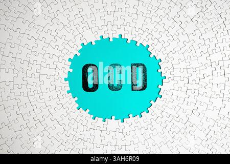 OCD-Wort auf türkisfarbenem Hintergrund, umgeben von einem kreisförmigen Puzzle Stockfoto