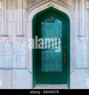 Grüne Tür mit getöntem Glas in einer hellen Steinfassade im Gothic Revival in Chicago. Stockfoto