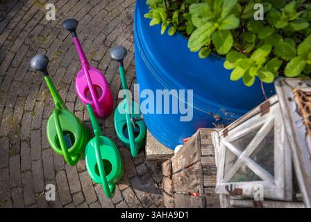 Gießkannen vor dem Regenfass, umweltfreundliche Regenwasserernte. Selektiver Fokus Stockfoto