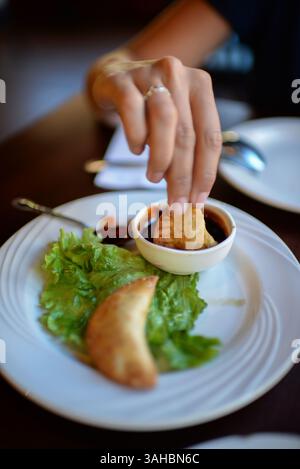 Hand von Frauen, die im Restaurant Soße auf Empanadas verteilen Stockfoto