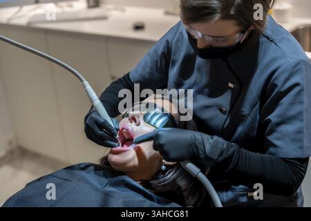 Zahnarzt mit Lasertechnologie für Zahnaufhellungsverfahren am Patienten in der modernen Zahnklinik Stockfoto