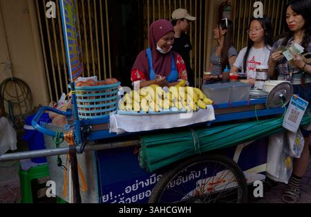 Ein fröhlicher Bananendessertverkäufer serviert Kunden in einer lebhaften Bangkok Straße Stockfoto