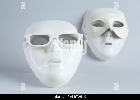 Theatermasken aus Plastik mit Sonnenbrille auf hellgrauem Hintergrund Stockfoto