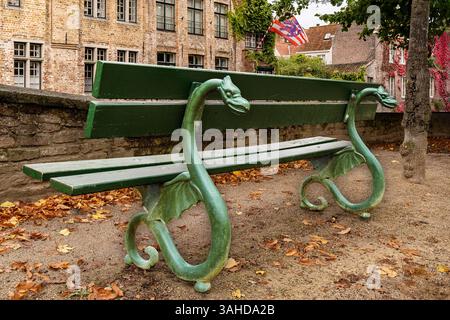Grüne Bank in der Nähe des Kanals Brügge Belgien mit ungewöhnlichem Drachenmotiv Stockfoto
