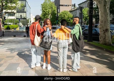 Rückansicht interrassischer Studentenfreunde, die sich während eines städtischen Meetups umarmen, bevor sie gemeinsam Spaß haben Stockfoto