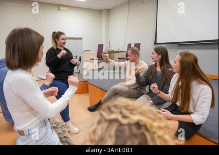 Junge Menschen kommunizieren in Gebärdensprache in einem Universitätsklassenzimmer. Stockfoto